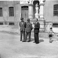 Uomini in conversazione di fronte alla Latteria del paese.